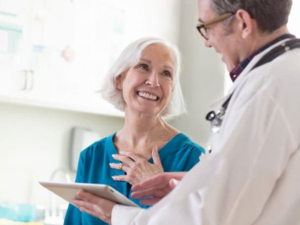 Mature woman smiling, looking at general practitioner