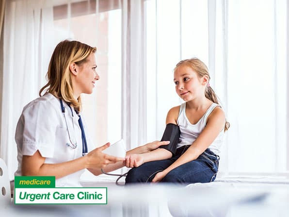 A healthcare professional measures a young girl's blood pressure